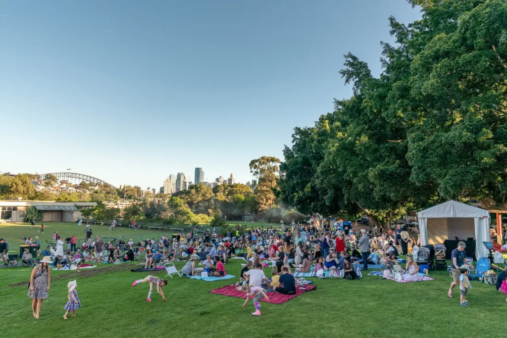 Wide view of families picnicking at Waverton Park with Sydney Harbour Bridge in the distance
