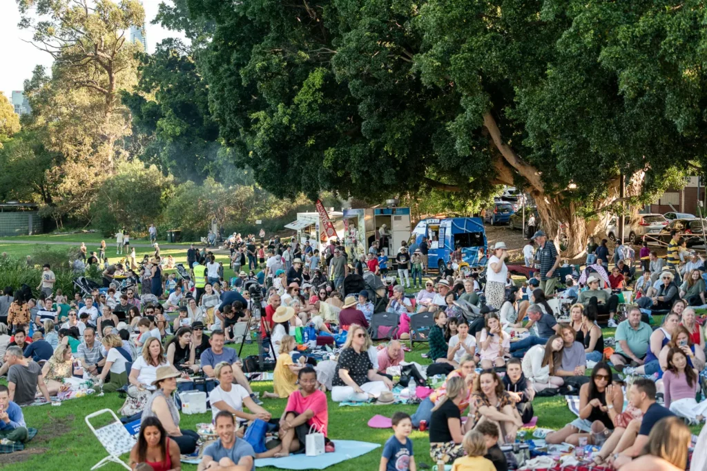Large crowd enjoying picnic blankets, food trucks and outdoor entertainment at Waverton Park